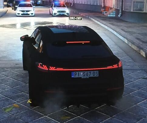 Чёрный автомобиль с сербским номером PI 067 DS на дороге, сзади видны полицейские машины